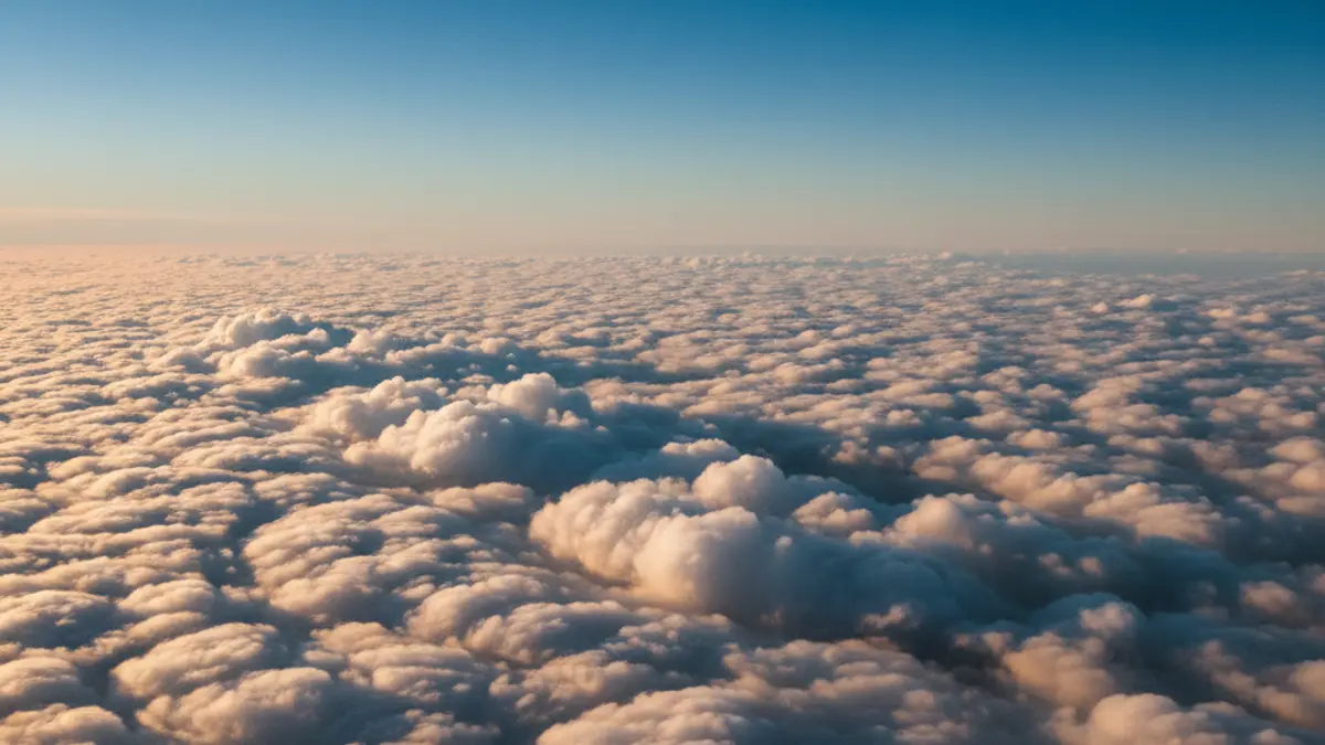 Weite, von der Sonne goldgelb beleuchtete Wolkenlandschaft aus der Vogelperspektive unter einem strahlend blauen Himmel.